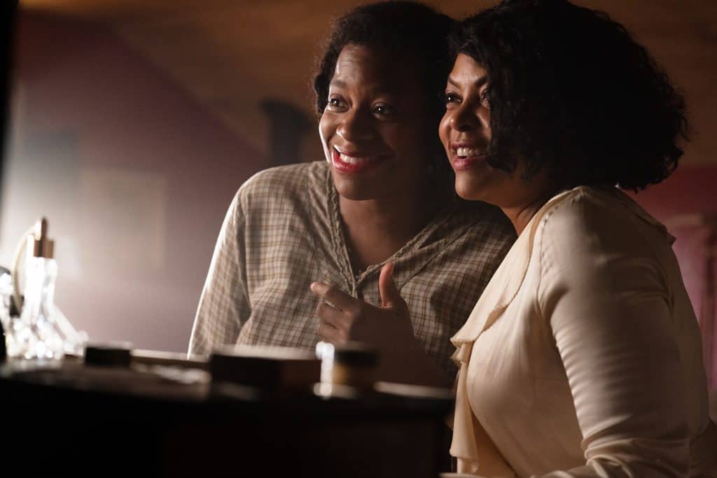 Two women smiling at the camera in a dark room.