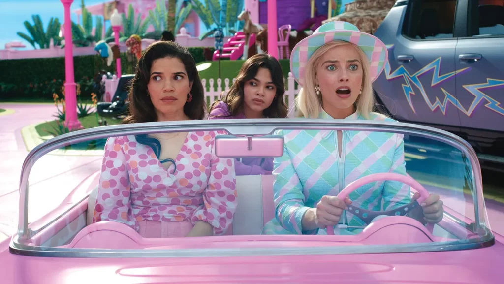 Three women are driving a pink car in a pink park.