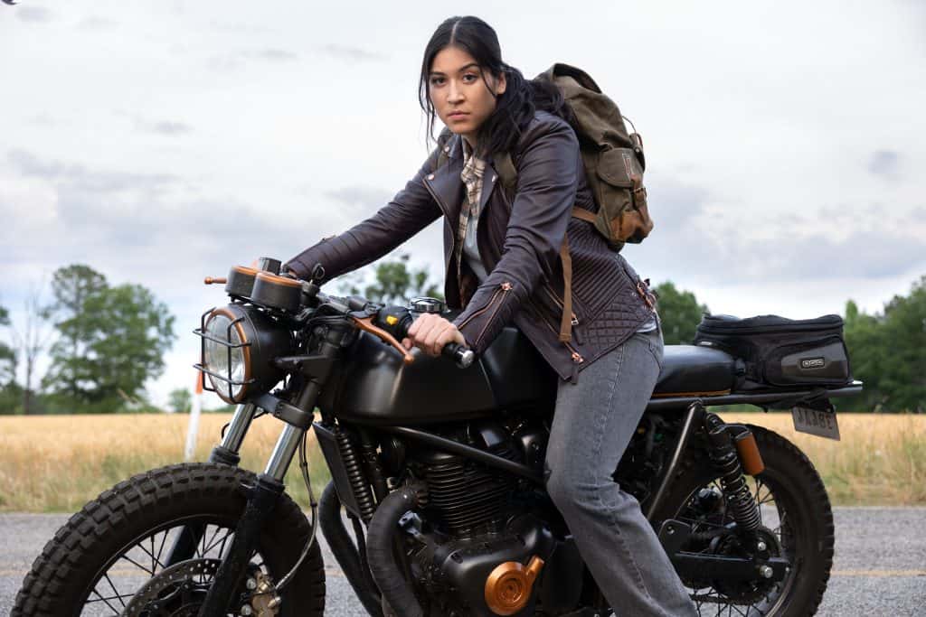 A woman is sitting on a motorcycle with a backpack.