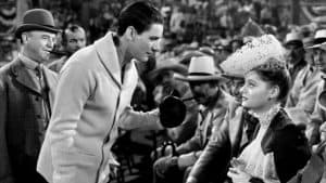 A man in a hat talking to a woman in a crowd.
