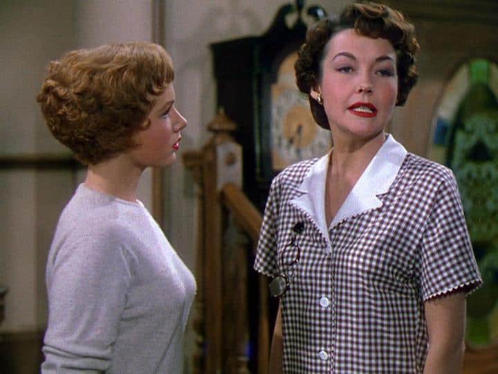 Two women standing next to each other in a living room.