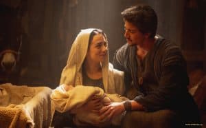 A man and woman holding a baby in a manger.