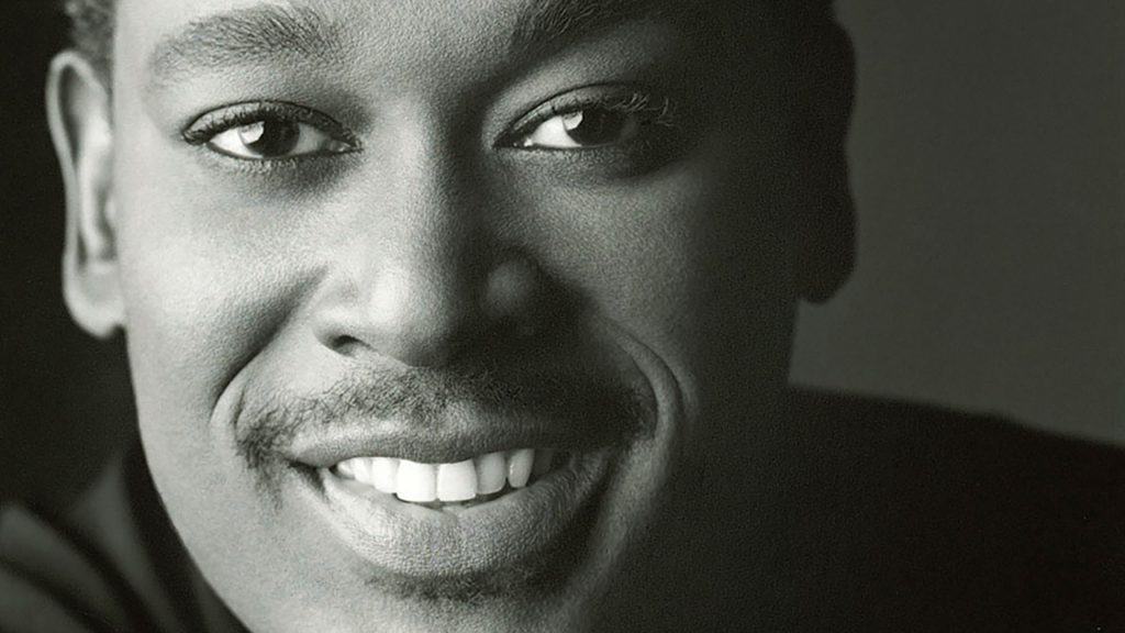 A black and white photo of a smiling man.