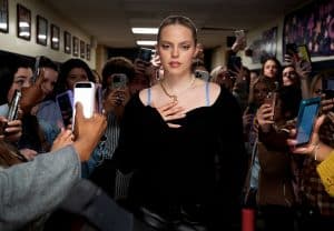 A woman is surrounded by people in a hallway.