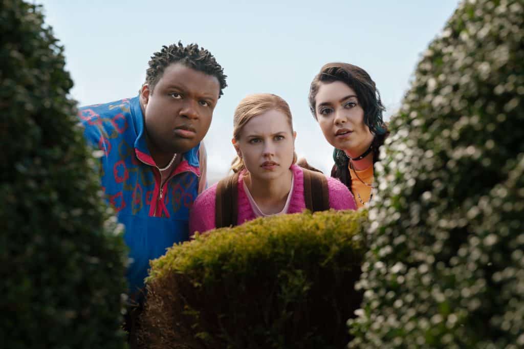A group of people standing in front of bushes.