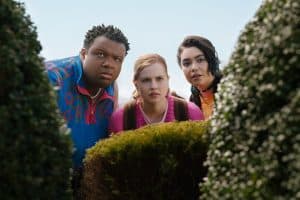 A group of people standing in front of bushes.