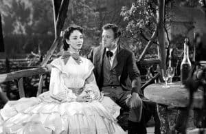 A man and woman sitting on a wooden bench.