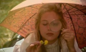 A woman under an umbrella with a magnifying glass.