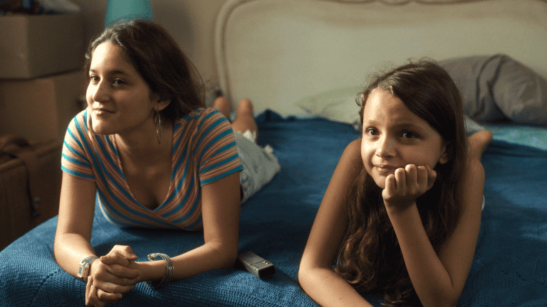 Two young girls laying on a blue bed.