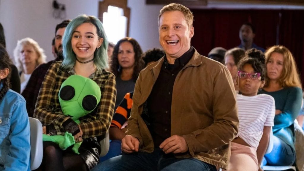 A group of people sitting in a room with a stuffed animal.