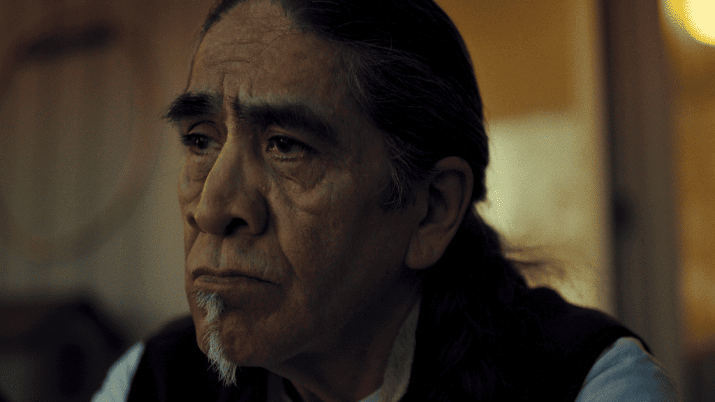 A man with long hair is staring at something.