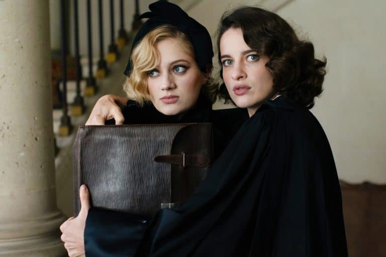 Two women in black cloaks holding a briefcase.