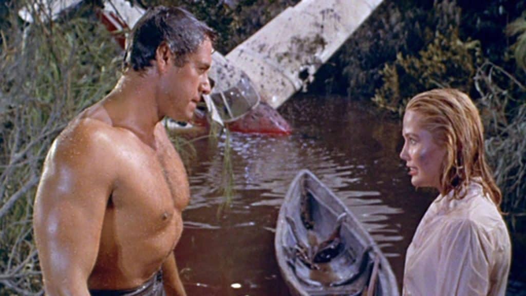 A man and woman standing next to a boat in the water.