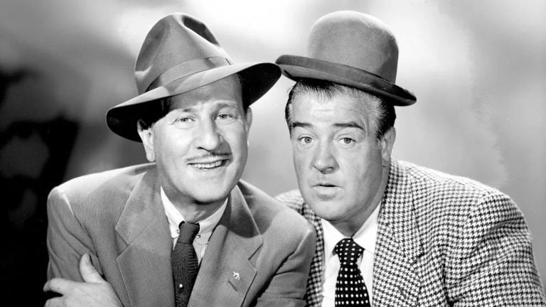 Two men in suits and hats are posing for a photo.