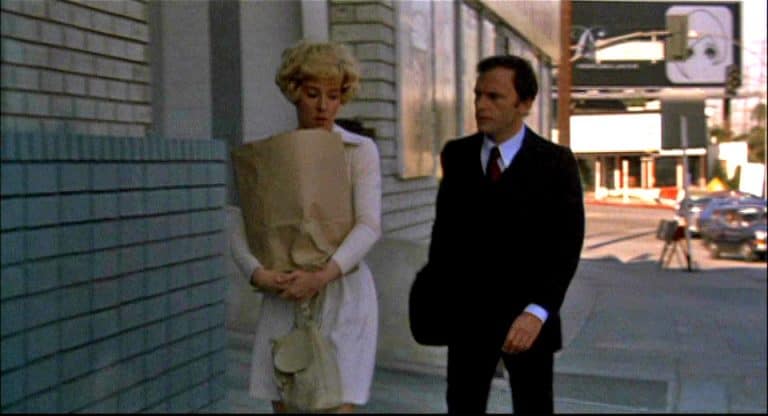 A man and woman walking down a sidewalk.