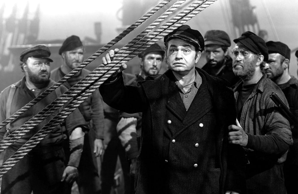 A black and white photo of a group of men on a ship.