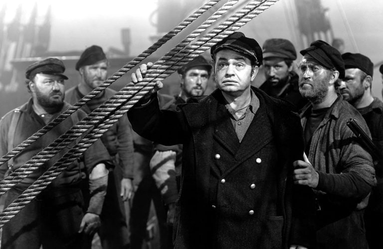 A black and white photo of a group of men on a ship.