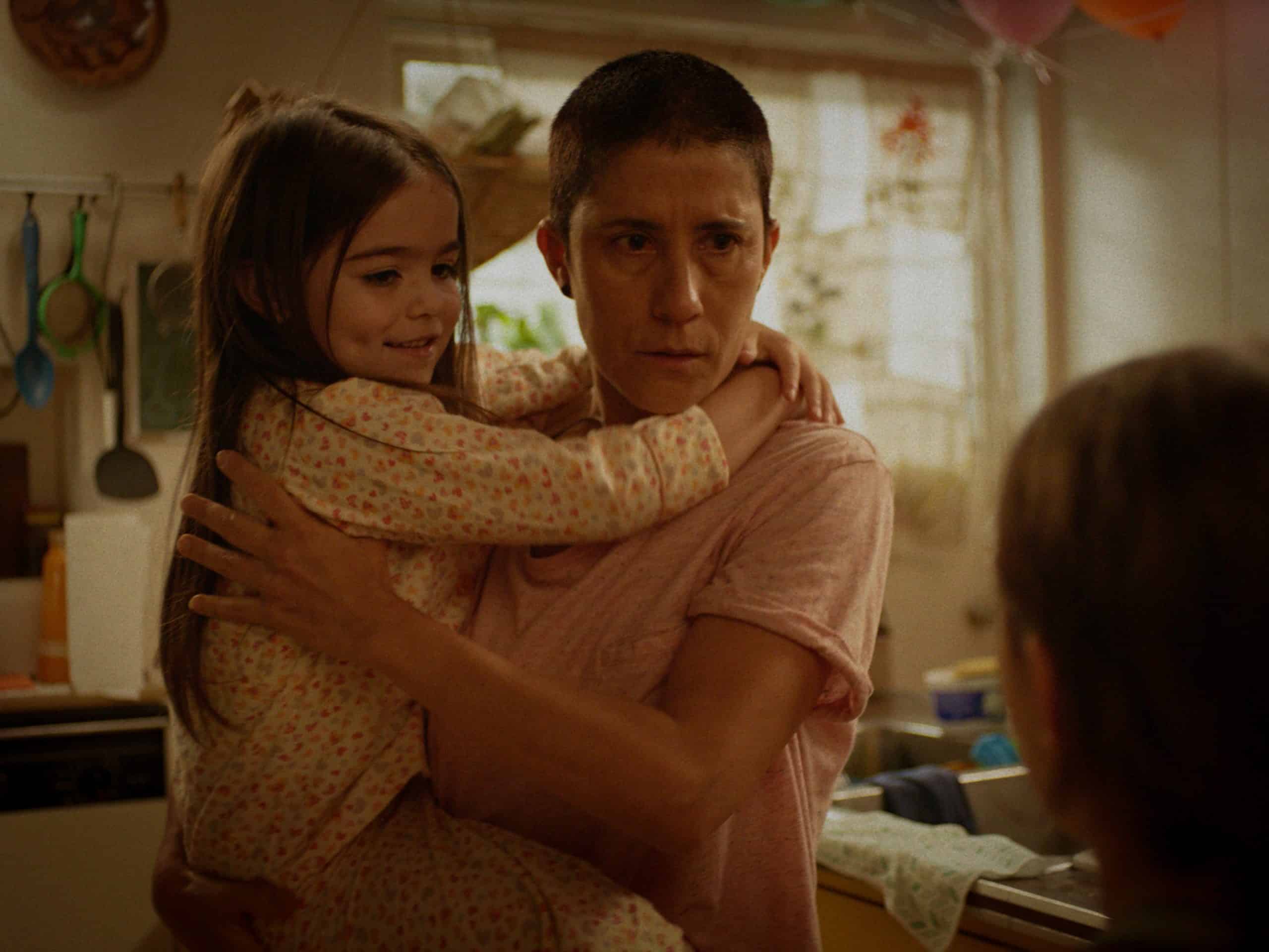 A woman is holding a little girl in a kitchen.