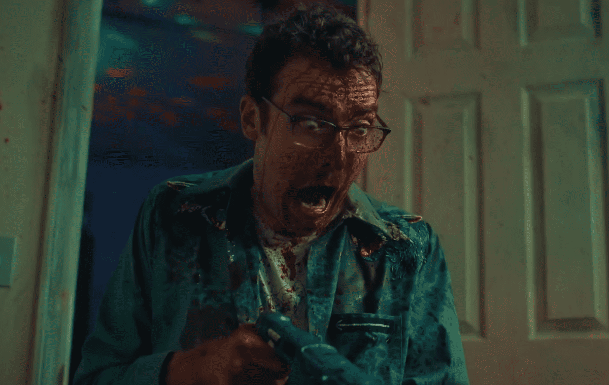 A man with blood on his face holding a gun.