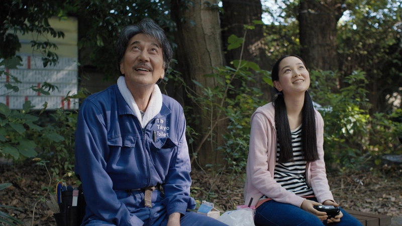 A man and woman sitting on a bench in the woods.