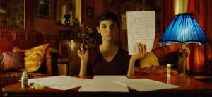 ‘Amélie’ Blu-Ray SteelBook Review – Fall In Love With This French Classic All Over Again A woman holding a piece of paper in front of a lamp.