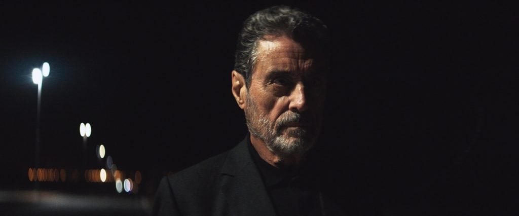 A man in a black suit standing in the dark.
