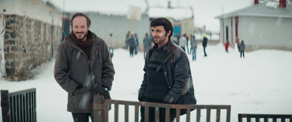 Two men standing next to each other in the snow.