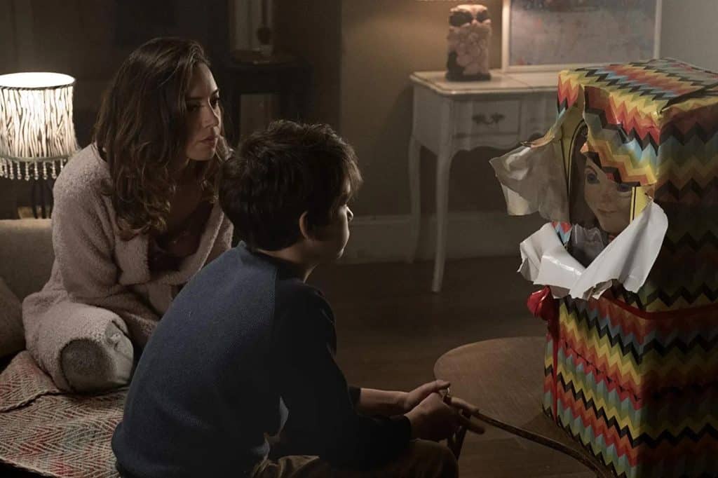 A woman and a boy sitting in front of a box.