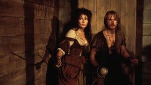 A man and a woman in medieval costume standing next to a wooden door.
