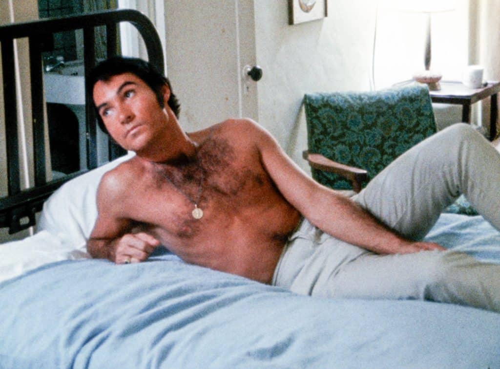 A shirtless man laying on a bed.