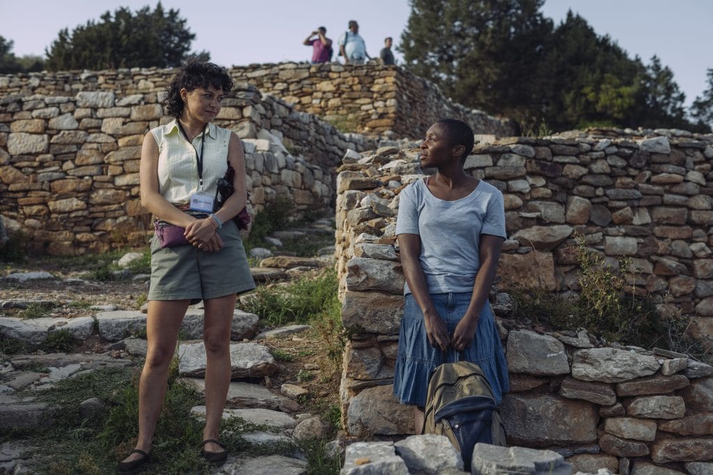 Two women standing next to a stone wall.