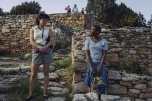 Two women standing next to a stone wall.