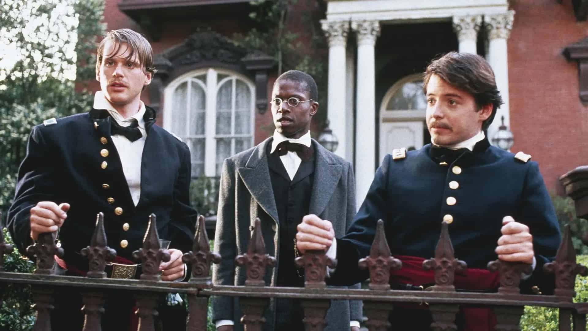 Three men in military uniforms standing next to a fence.