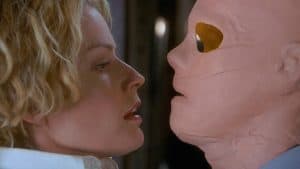 A woman is kissing a mannequin head.