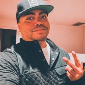 A man in a black hat making a peace sign.