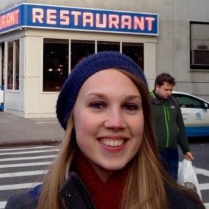 A woman standing in front of a restaurant.