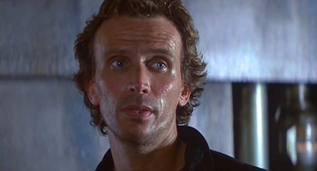 A man in a black shirt is staring at the camera.