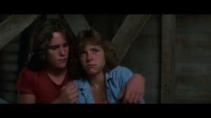 A boy and a girl sitting next to each other in a barn.