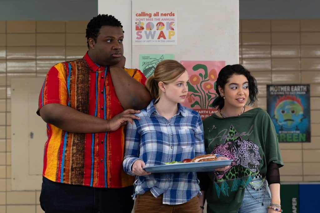 Three people standing in a hallway with a tray of food.
