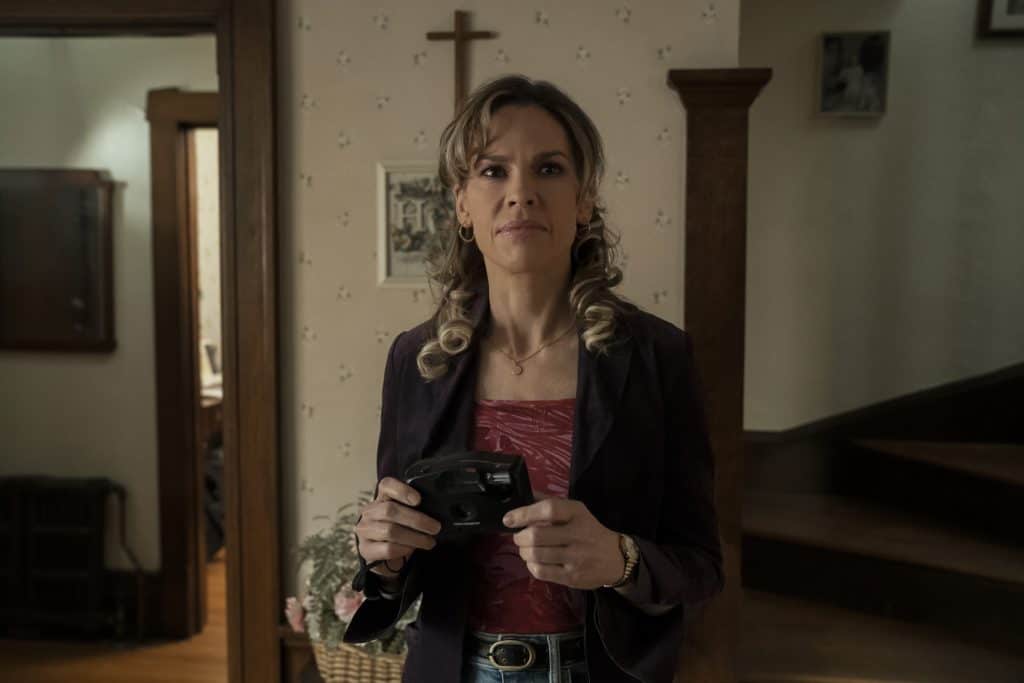 A woman standing in a room holding a camera.