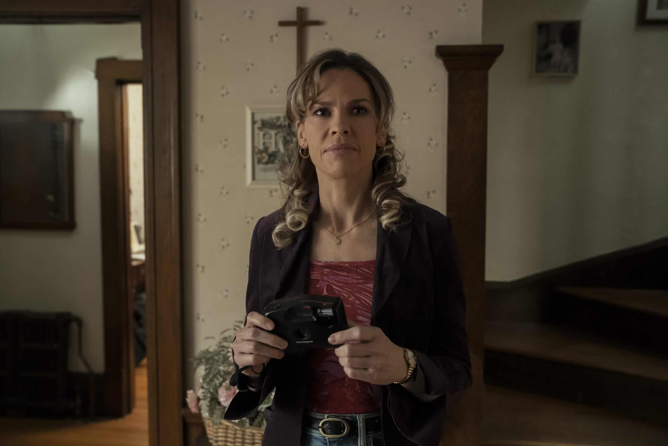 A woman standing in a room holding a camera.