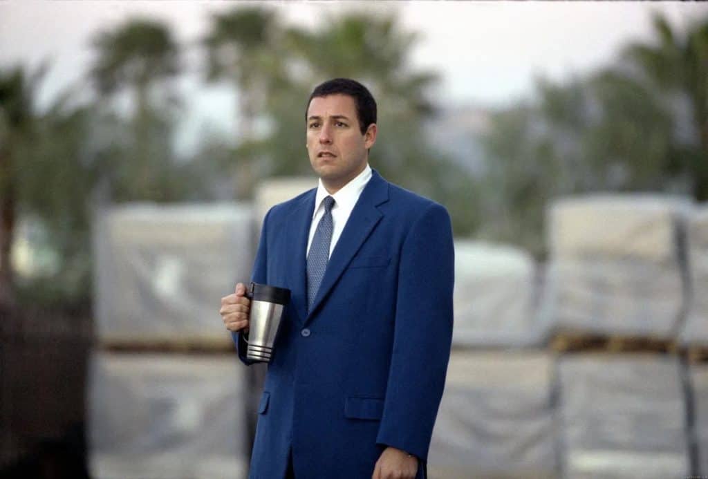 A man in a suit holding a thermos.