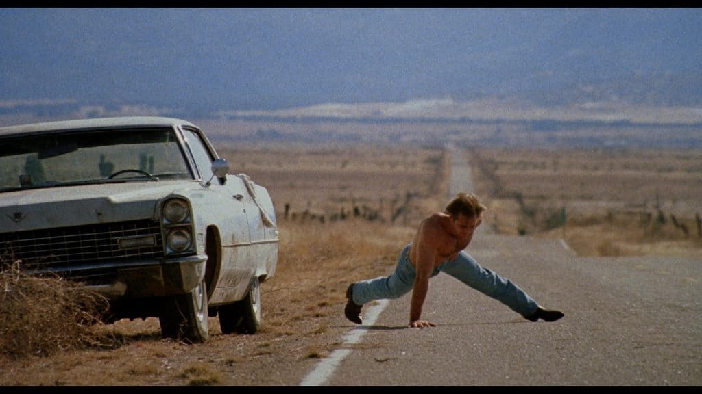 A man bending over to get a car.