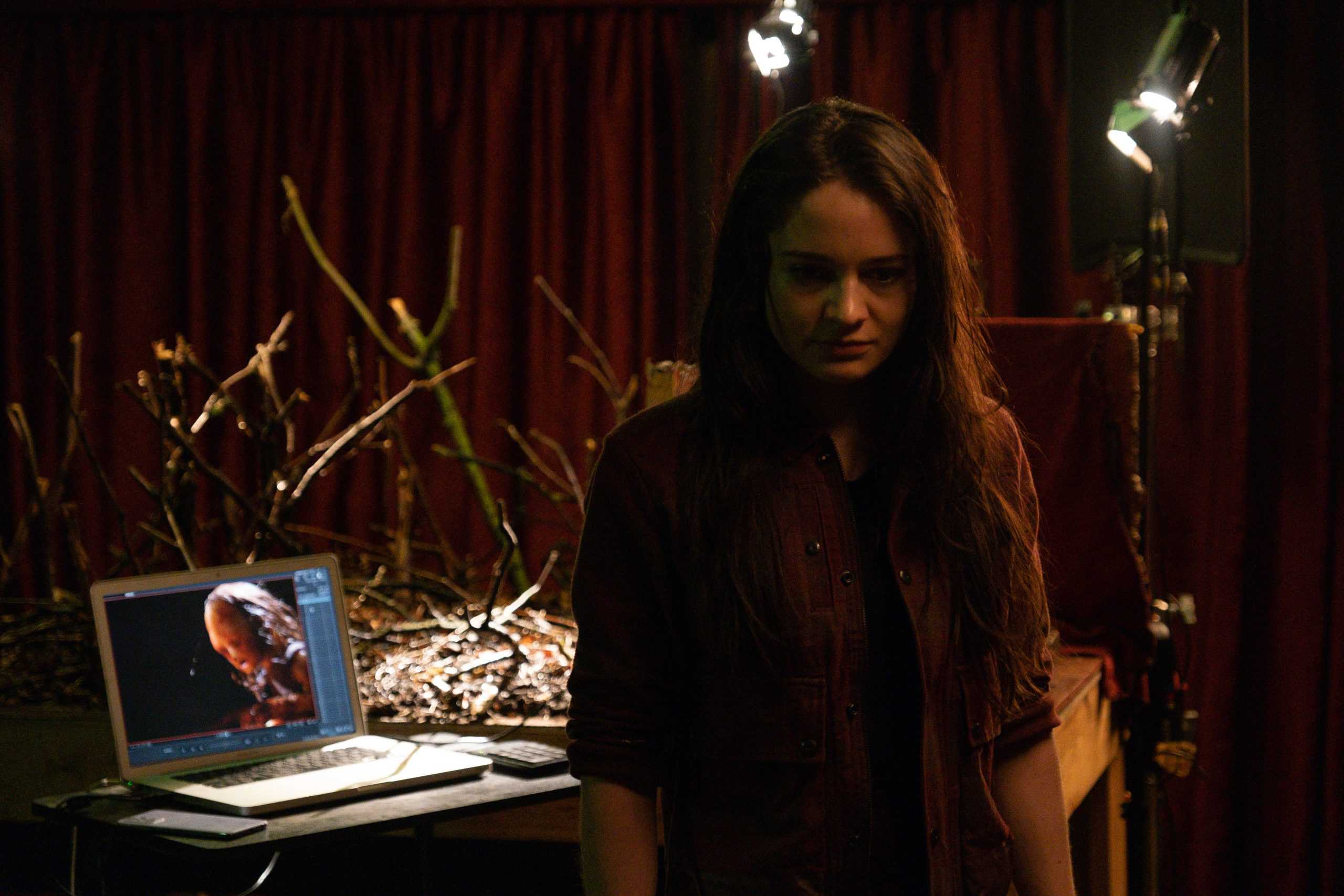 A woman standing in front of a laptop.