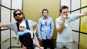 A group of men standing in an elevator with a baby in their arms.