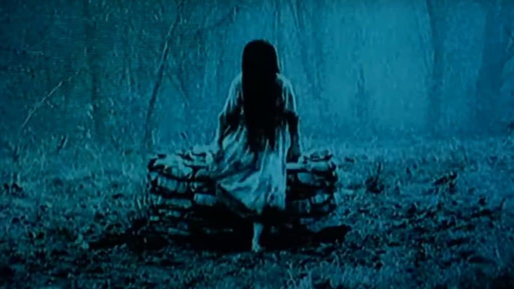 A woman with long hair standing in the woods.