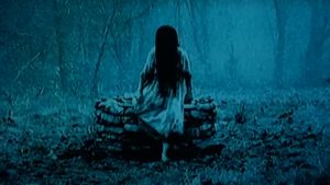 A woman with long hair standing in the woods.