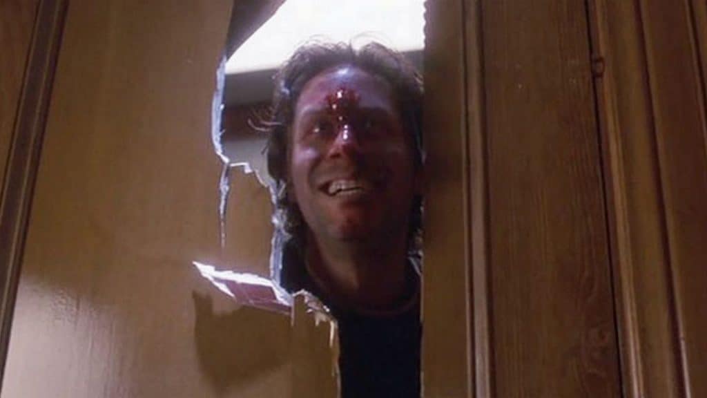 A man peeking out of a hole in a door.
