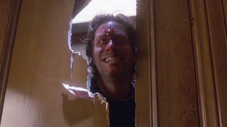 A man peeking out of a hole in a door.