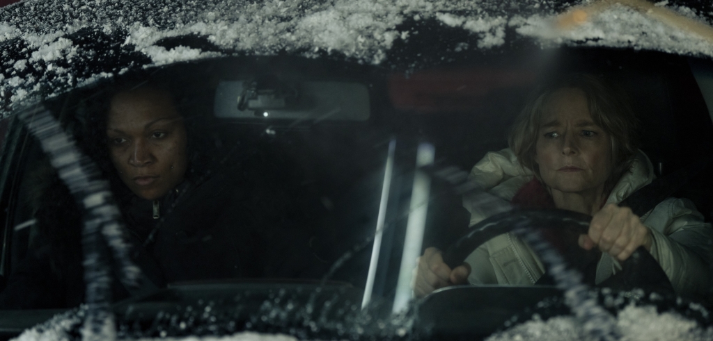 Two women sitting in a car covered in snow.